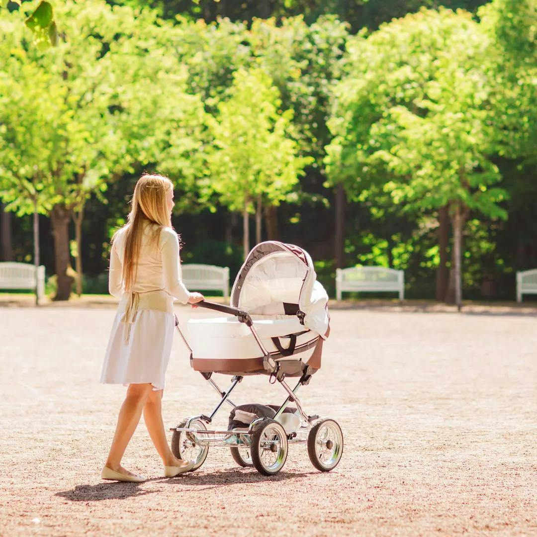 A mother walks her stroller in the park.